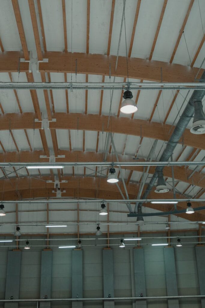 High-angle view of a spacious industrial ceiling featuring pendant lights and steel design elements.